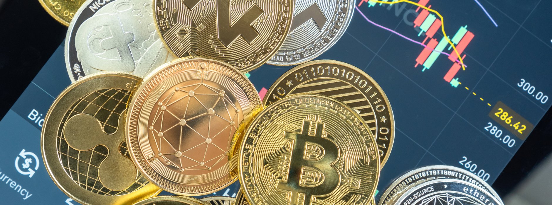 multiple golden crypto coins in front of a mobile device showing a crypto chart