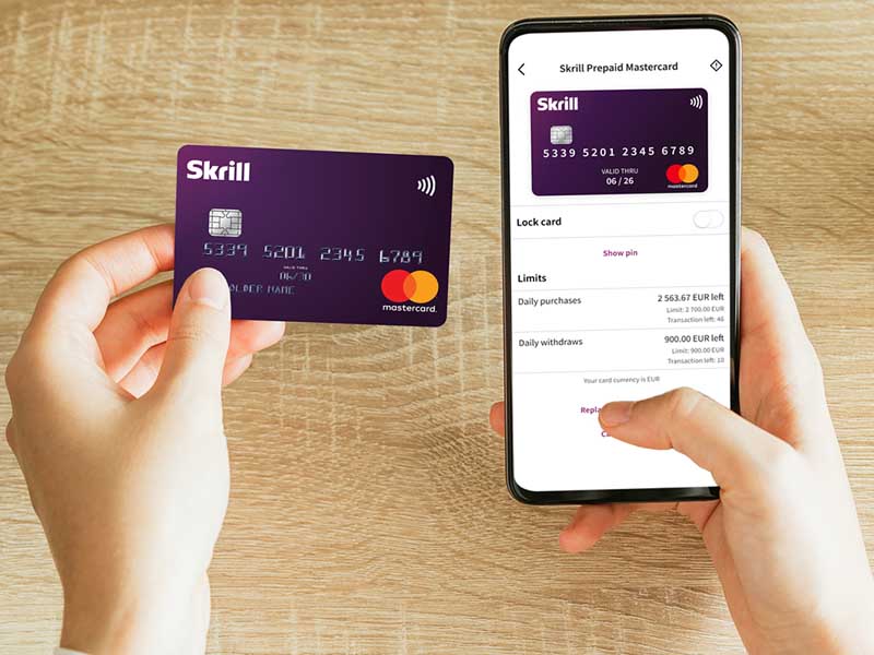 user holding a Skrill card and a mobile with the Skrill app open
