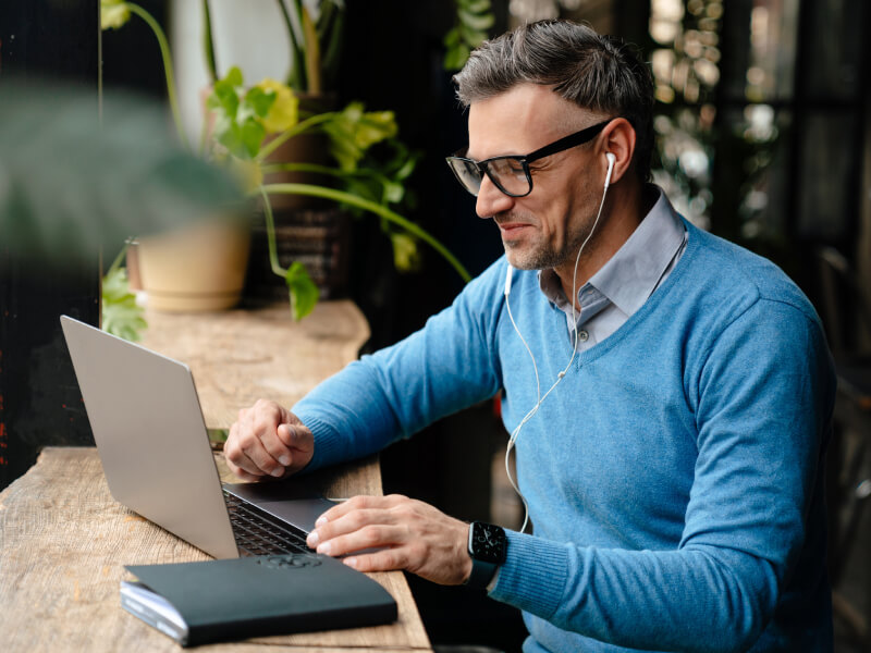 Man wearing headphones while working on his laptop