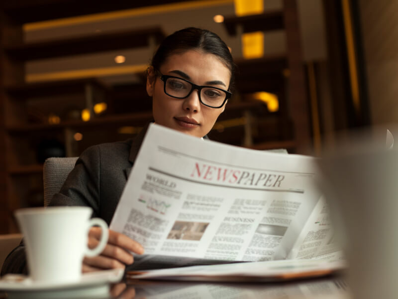 Woman reading a newspaper while enjoying her coffee