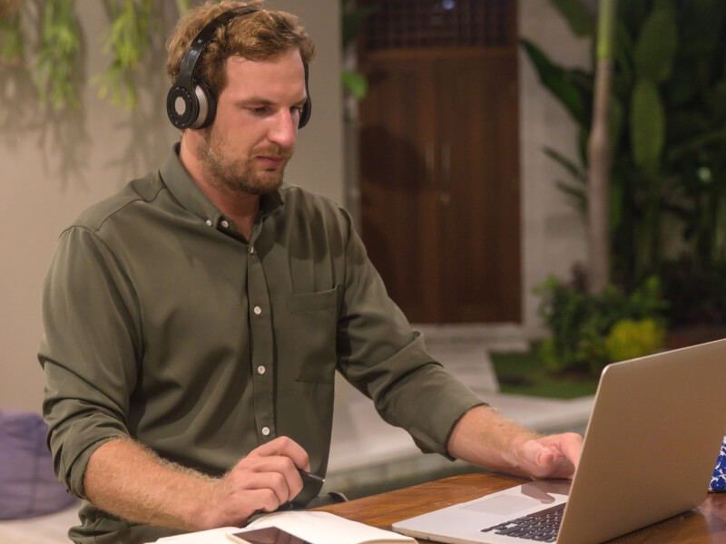 Man wearing headphones while looking at his laptop screen