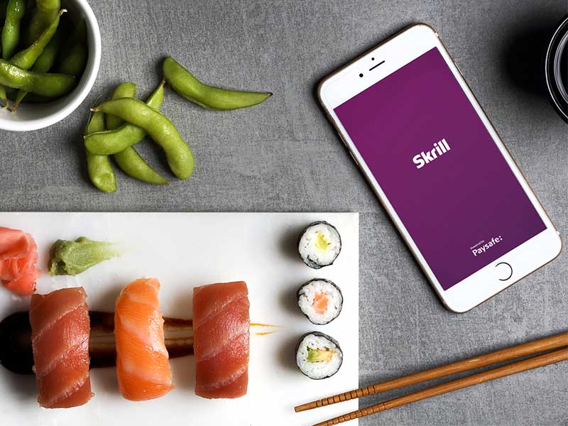 phone with open Skrill app next to a sushi set