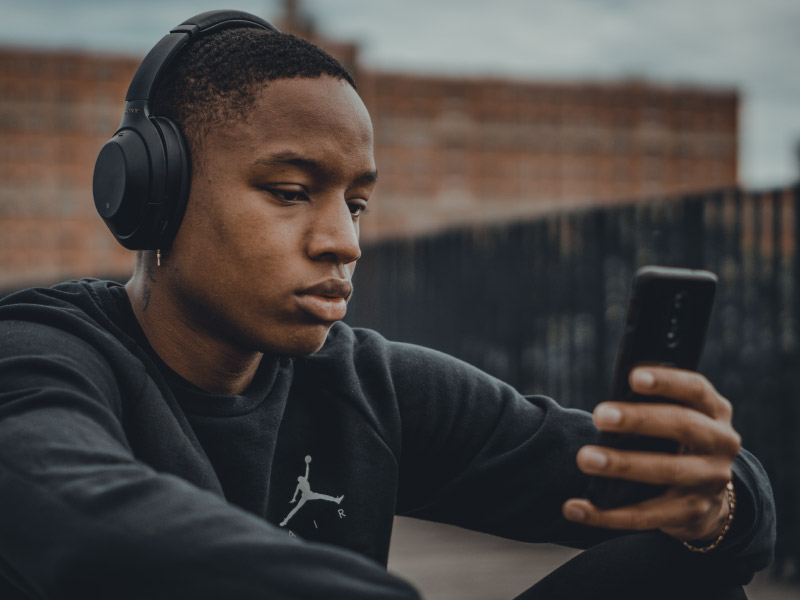 young man with headphones holding a mobile phone