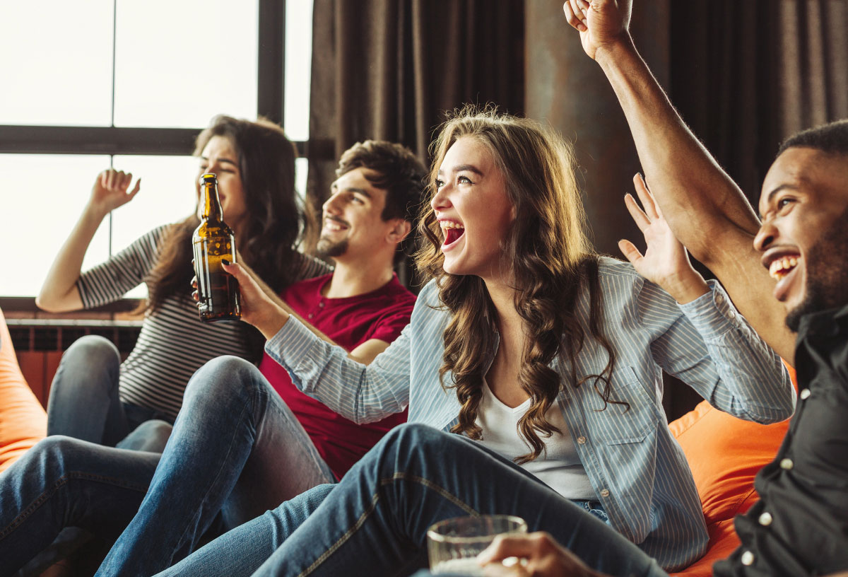a cheering group of friends on a couch watching a sports game