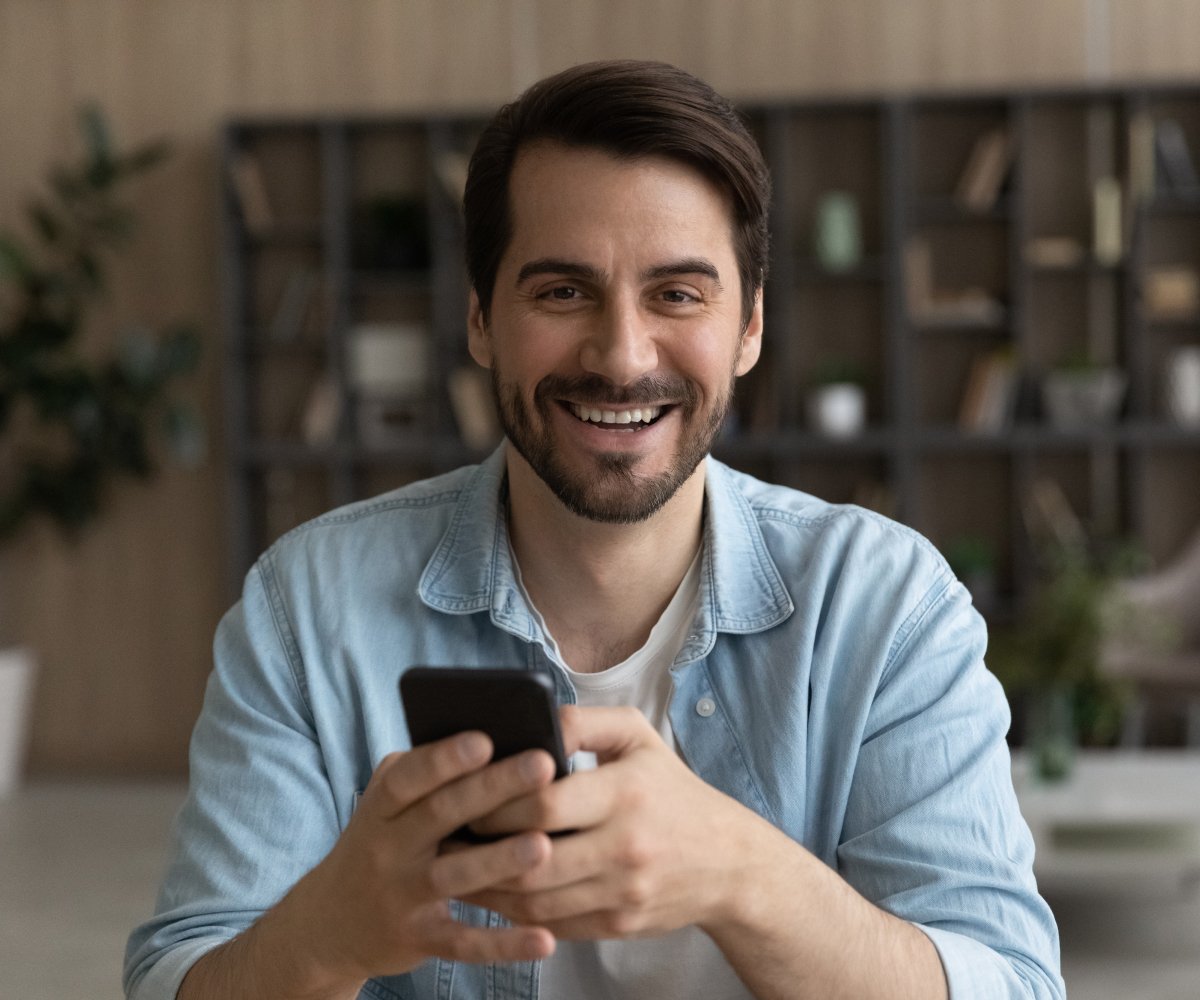 use various deposit methods with Skrill; smiling man holding his phone