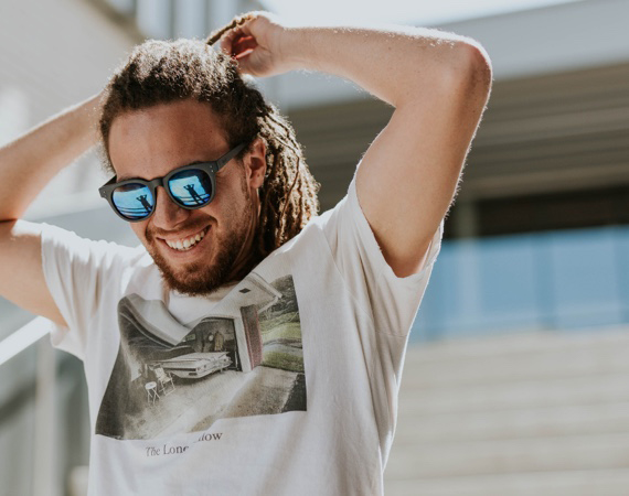 man with dreadlocks and sun glasses smiling and walking down the stairs